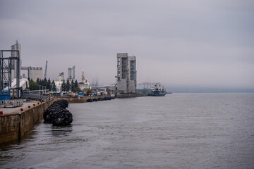 Industrial port with ships and silos on a cloudy day