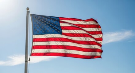 The American flag waving in the wind against a clear blue sky.