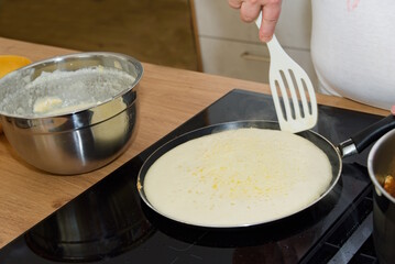 K&ouml;chin bereitet Palatschinken am K&uuml;chenherd zu