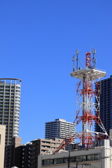 Obraz premium Telecommunication tower and skyscrapers under a clear blue sky in the city