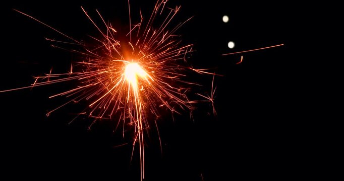 Wire sparklers with bright golden sparks on a black backdrop, perfect for celebration themes.