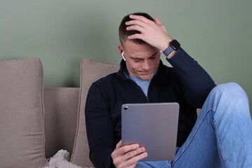 young man using tablet, stressed man video chatting on his tablet