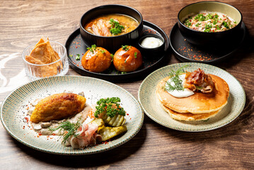 A mouth-watering spread of traditional Eastern European dishes, featuring savory potato dumplings, rich soups, and fluffy pancakes on a rustic wooden table.