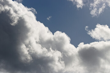 Soft white clouds drifting across a clear blue sky, creating a calm atmospheric background with natural light and open space.