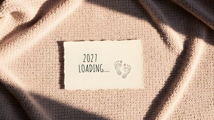A warm and delicate announcement of the coming of a new life with the text 2027 LOADING... and little feet footprints.