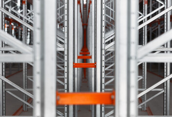 Metal warehouse pallet or shelf rack, close-up of the connection node. Vertical perforated rack and horizontal beams, painted orange. Industrial logistics structure for warehouses, stores, archives.