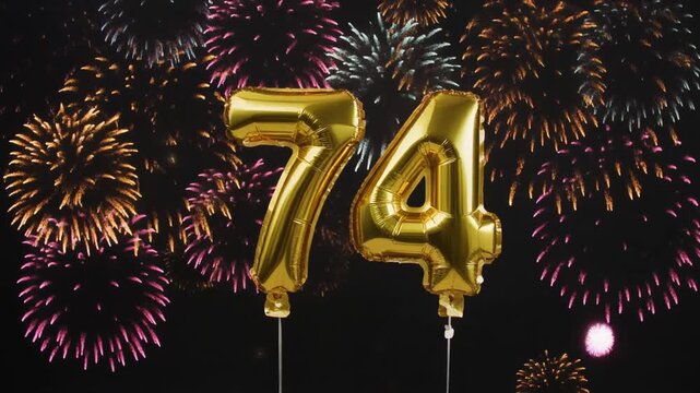 Gold balloon number 74 with fireworks in the background. Festive scene for birthday or anniversary party
