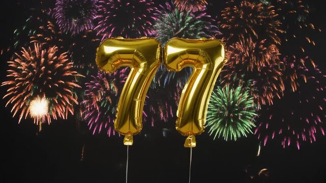 Gold balloon number 77 with fireworks in the background. Festive scene for birthday or anniversary party