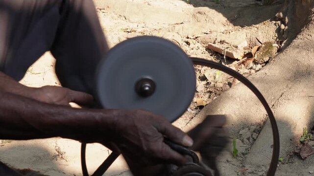 person using a traditional, mobile knife-sharpening machine. 