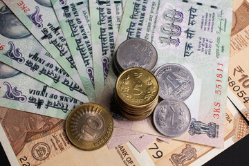 Close-up image of Indian rupee notes (INR) of different values and stack of coins. Concept of cash savings, financial profit and security, Indian economy.