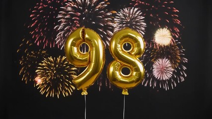 Gold balloon number 98 with fireworks in the background. Festive scene for birthday or anniversary party