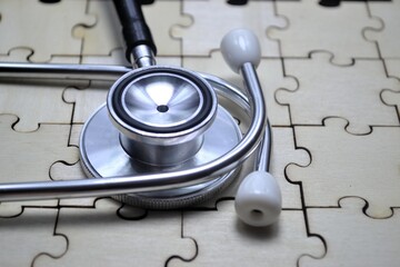Stethoscope placed on wooden puzzle surface symbolizing the complexity of medical diagnostics and...