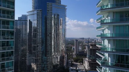 Drone flight through tall modern buildings in Miami city center filmed in daylight showing dense urban architecture and fast growing metropolitan city