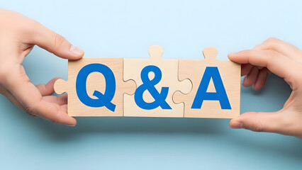 Two hands holding three wooden puzzle pieces together forming abbreviation q and a for questions and answers concept on light blue background representing communication and support services