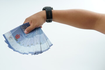 Hand holding Malaysian ringgit banknote on white background representing cash payment, personal...