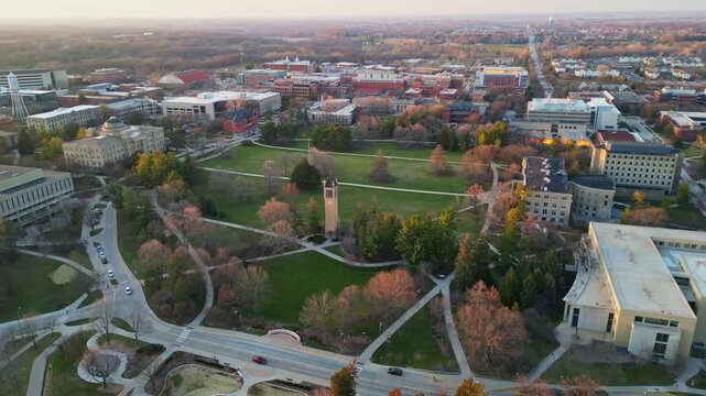 An expansive aerial view of the Iowa State University campus in Ames, Iowa, showcasing the central green spaces, numerous academic buildings, and the iconic campanile.