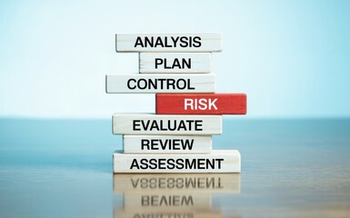 A stack of wooden blocks presenting a business process with words like analysis plan control risk evaluate review and assessment on a reflective surface with a light blue background in soft lighting r