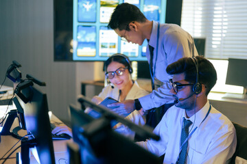 Professional diverse team in headsets collaborates in a control center. Monitoring live data on screens and tablets for international flight. Network security, and corporate operation application