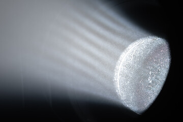 Close up of dust particles illuminated by a strong spotlight beam, revealing light rays and circular lens reflections.