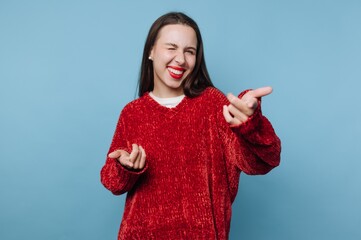 Woman in red sweater playfully winking and pointing fingers.