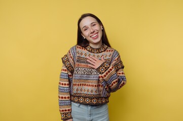 A smiling woman in a colorful patterned sweater against a yellow background.