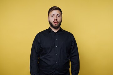 Obraz premium A surprised man in a black shirt against a yellow background.