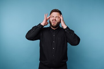 Fototapeta premium Man in black shirt expressing frustration against blue background