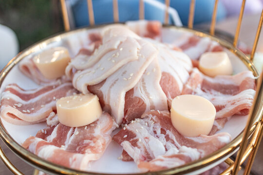 Sliced raw pork belly with layers of fat and meat on a plate, traditional ingredient for Korean BBQ or Thai Moo Krata, delicious fatty pork for grilling and barbecue concept.