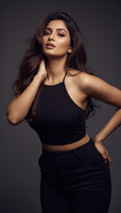 Naklejka premium Confident Indian Woman Posing in Stylish Black Crop Top Studio Portrait