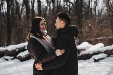 Young couple embraces in winter landscape with snow and trees