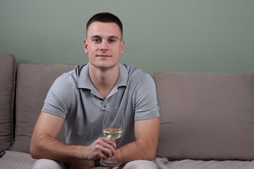 portrait of a young white male sitting on a couch and holding a glass of white wine