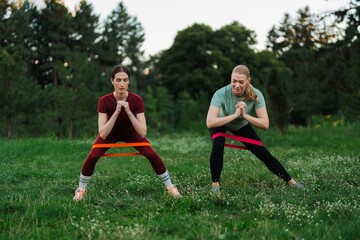 Fitness enthusiasts engaging in outdoor resistance band workout at sunset