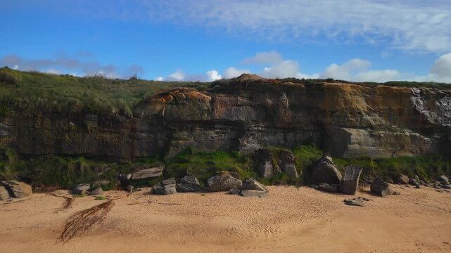 Aerial drone flying forward over sandy beach toward a rocky cliff at Santa Cruz beach in Portugal
