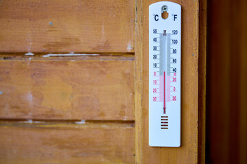 Wall-mounted thermometer displaying temperature in celsius and fahrenheit