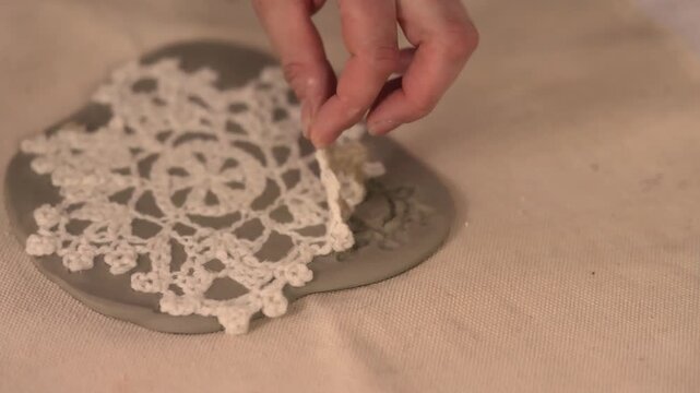 Close up of hands using a fabric star tool to compress clay forming a handmade Christmas ornament showing cozy Scandinavian craft hobby and creative process in warm festive setting
