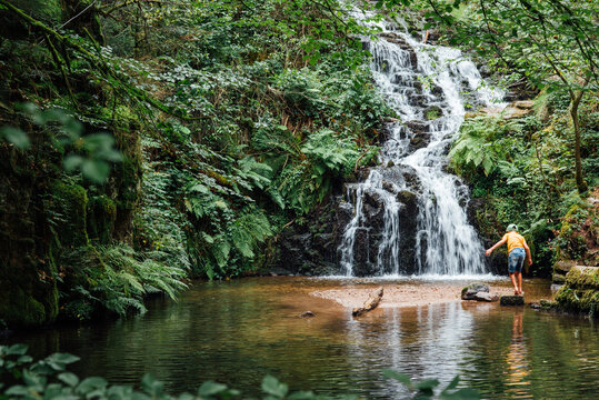 un enfant jouant vers une cascade d'eau. Chute d'eau &agrave; la cascade de Faymont. 
Enfant s'amusant dans l'eau en pleine for&ecirc;t durant l'&eacute;t&eacute; caniculaire.