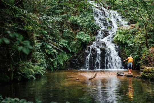 un enfant jouant vers une cascade d'eau. Chute d'eau &agrave; la cascade de Faymont. 
Enfant s'amusant dans l'eau en pleine for&ecirc;t durant l'&eacute;t&eacute; caniculaire.