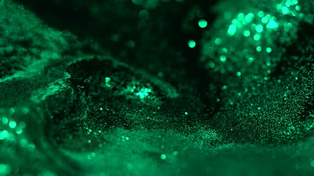Green liquid abstract shimmering glitter particles moving across a dark macro surface, forming a smooth cinematic texture ideal for backgrounds, overlays, luxury visuals and design elements.