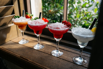 Four different colored margaritas are lined up on a wooden table