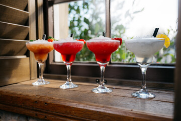 Four martinis are lined up on a wooden table