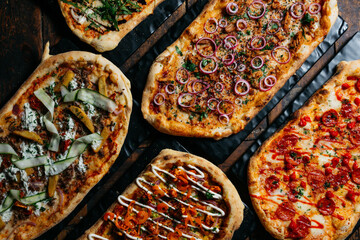 A row of pizzas with different toppings, including pepperoni, onions, and cheese