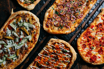 A row of pizzas with different toppings, including one with onions