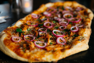A large pizza with onions and meat toppings