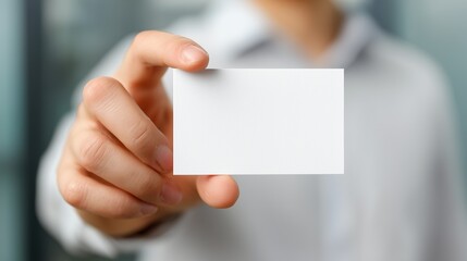A crisp, professional close-up of a business man's hand extending forward, presenting a perfectly blank business card directly to the viewer.