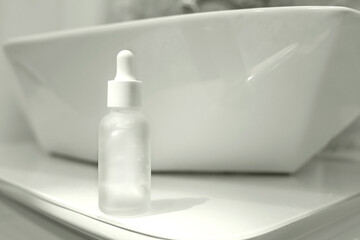 Minimalist skincare concept with frosted glass serum bottle in modern bathroom setting.