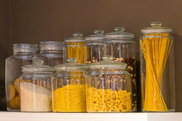 Glass jars with essential domestic food inside kitchen pantry interior