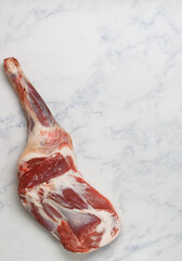 Raw whole shoulder of lamb on a marble table. Selective focus, copy space
