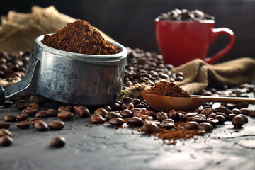 Espresso handle filled with ground coffee and coffee cup with roast coffee beans