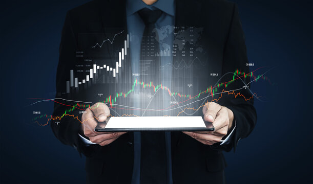A businessman in a suit holds a tablet displaying dynamic financial data and graphs, symbolizing modern analysis and strategy in business and investment. Scalp - Powered by Adobe