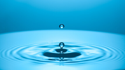 A water droplet creating ripples on a serene surface, a symbol of purity and tranquility. The droplet hangs suspended mid-air before impact